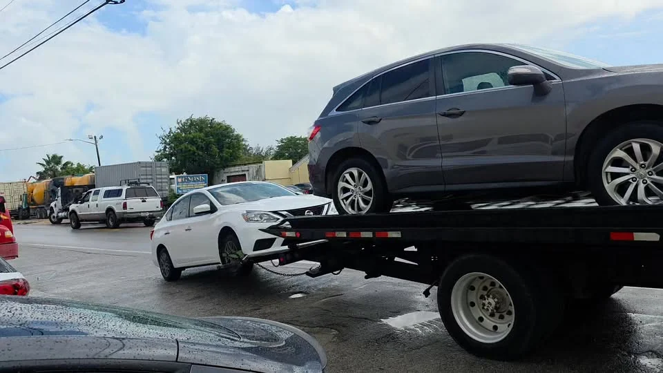 Morley Towing Services flatbed hauling an SUV while towing a sedan behind it in South Florida