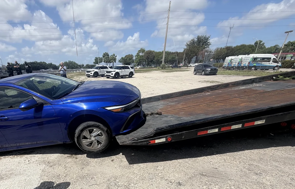 Morley Towing Services winching a wrecked sedan onto a flatbed at an accident scene in Miami-Dade County